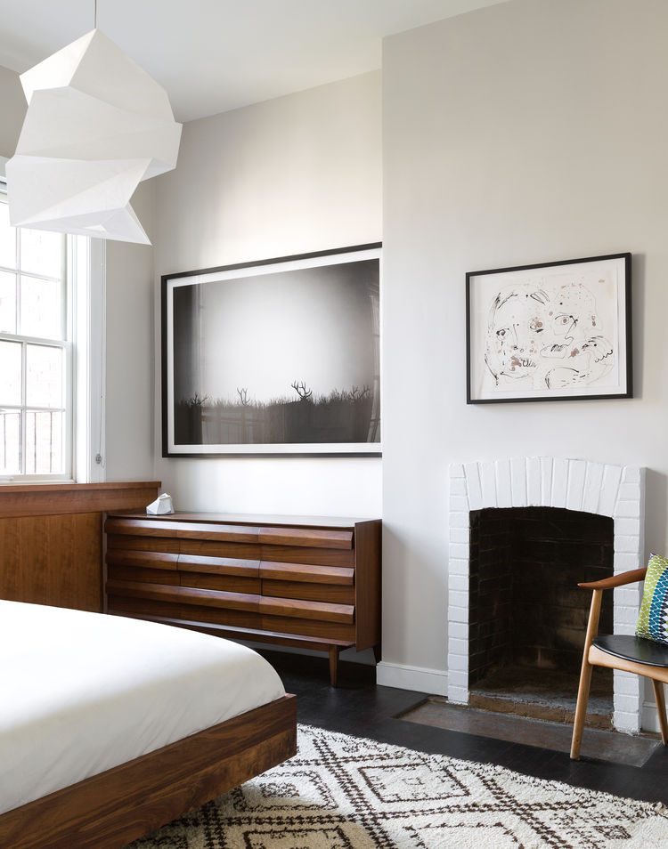 artworks and a fireplace give the bedroom an original look