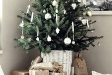 a pretty tabletop Christas tree with silver ornaments and candles put in a white basket is a beautiful and romantic thing