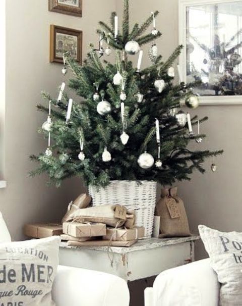 a pretty tabletop Christas tree with silver ornaments and candles put in a white basket is a beautiful and romantic thing