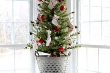 a small Christmas tree decorated with little pinecones, red ornaments and tiny stockings looks rustic and pretty