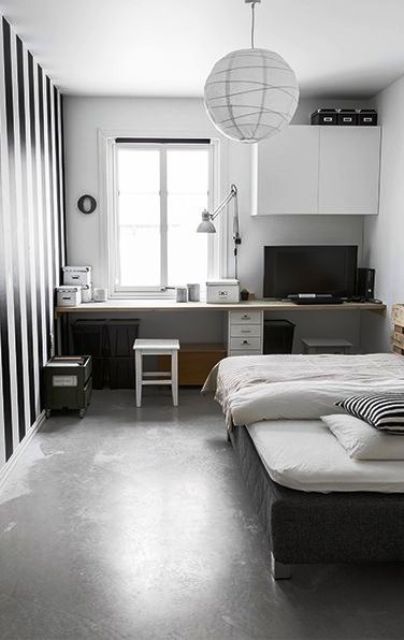 a conemporary teen room with a study space by the window, a windowsill desk, a cabinet, a bblack bed and a striped accent wall