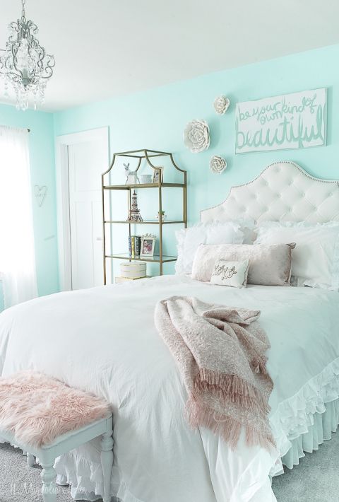 a romantic vintage teen room with mint blue walls, a tufted white bed, a refined storage shelf, some faux blooms and a crystal chandelier