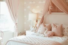 a blush and white girl’s bedroom with pink flamingo wallpaper, a white bed with pink and white bedding, a pink canopy and a crystal chandelier