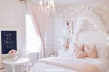 a blush flamingo printed wallpaper wall, a white bed with a lit up cnaopy, pink and white bedding, vintage dinign set and a crystal chandelier
