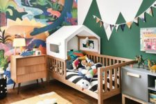 a bright and fun jungle-themed kids’ bedroom with a bold artwork, a house bed and colorful jungle-inspired toys