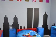 a colorful Marvel super hero themed kids’ room done in blue, red and black, with emblems and bright bedding