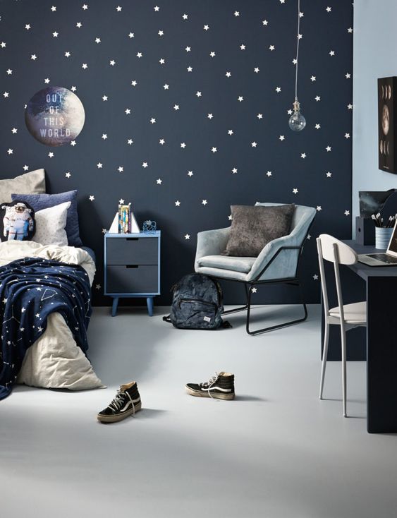a cool space-themed kid's room done in navy, grey and white, with a star pattern incorporated and blue and grey furniture