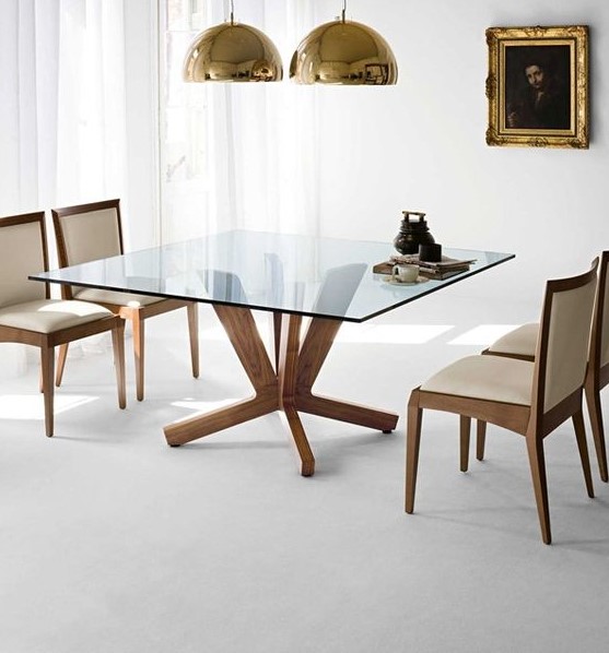 a square dining table with a glass tabletop and cool and stable wooden legs for a clean modern dining room