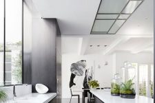 a contemporary black and white kitchen with white countertops, a window as a backsplash and built-in lights