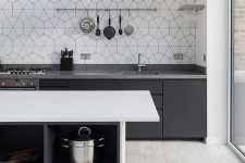 a contrasting Scandinavian kitchen in black, grey and white, black cabinets with grey countertops, a white kitchen island and hex tiles