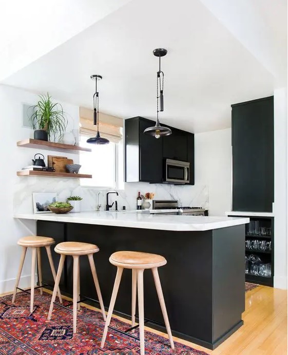 A cozy modern black and white kitchen with matte black cabinets, white marble countertops, built in appliances, open shelves and pendant lamps