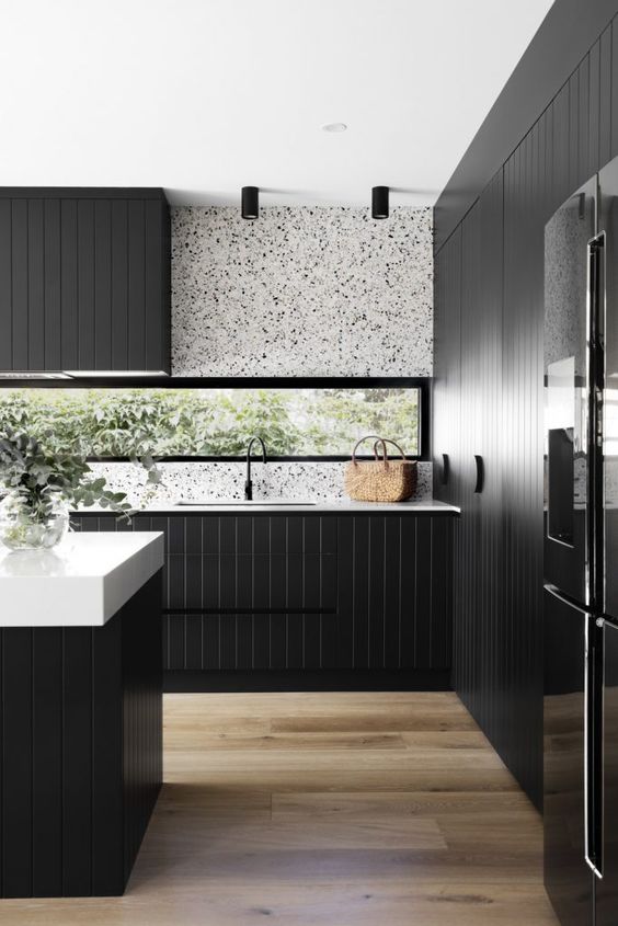 a sleek modern kitchen with black planked cabinets, a white terrazzo backsplash, white countertops and black fixtures is a lovely idea