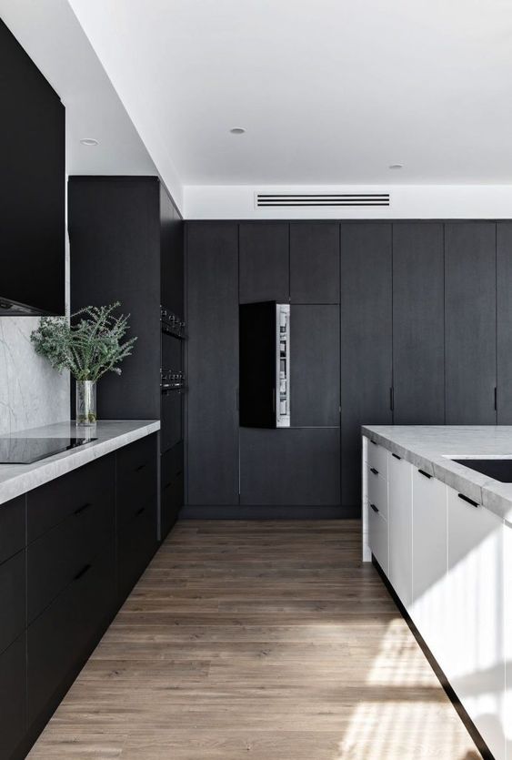 A sophisticated minimalist kitchen with matte black cabinets, white marble countertops, a white kitchen island and some built in lights