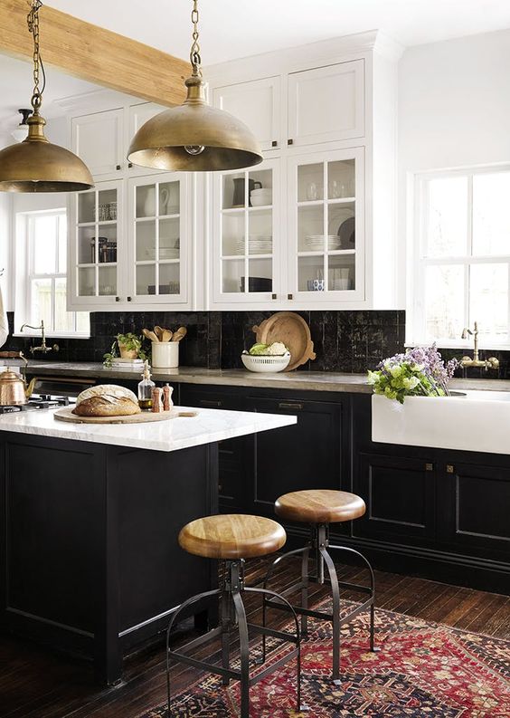 A vintage inspired kitchen with black shaker cabinets, white countertops and a black Zellige tile backsplash, metal pendant lamps