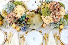 a bright and elegant Thanksgiving tablescape with bold blooms, green pumpkins, candles, gold chargers and cutlery and some berries