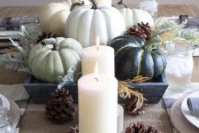 a neutral Thanksgiving centerpiece of green pumpkins, candles and pinecones is a great idea for a rustic tablescape