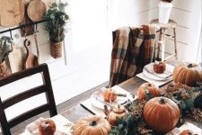 a simple rustic Thanksgiving table with a lush greenery runner, orange pumpkins and gourds, copper teapots and mugs