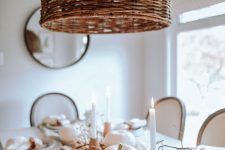an ethereal white Thanksgiving tablescape with berries, pumpkins, elegant porcelain and linens, candles in wooden candleholders