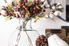 cozy fall decor with cotton branches, berries and greenery and a wooden bowl with a gourd and pinecones