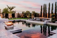 a neutral outdoor space with a geometric pool, white stone tiles, a fire pit and a waterfall is a very spectacular and cool space