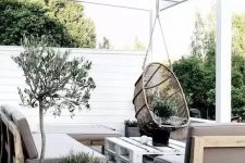 a Scandinavian outdoor living room with concrete planters, wooden and pallet furniture and a hanging rattan chair