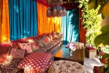 a colorful Morocco-style outdoor living room with turquoise and orange curtains, soft seating furniture with bright upholstery, potted greenery