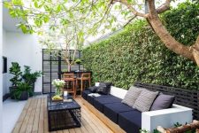 a contemporary outdoor living room with stylish furniture, a small bar and a living wall as a backdrop