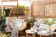 a cozy rustic terrrace in natural tones with wicker curtains, wicker furniture, a rattan chair and potted blooms and greenery