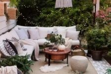 a lively neutral outdoor living room with a corner sofa, a white pendant lamp, greenery and some boho accessories decorated for fall
