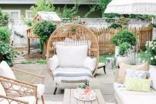 a lively summer terrace with rattan furniture, a comfy sofa, printed textiles, a low table and lots of greenery around