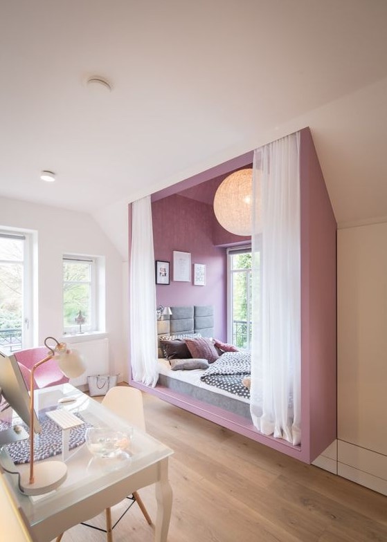 An ultra modern and bold teen girl bedroom with a purple alcove sleeping space by the window and a white studying zone