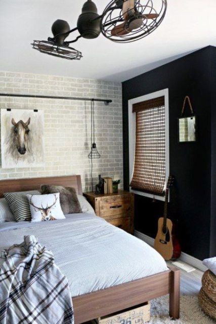 a contemporary teen bedroom with a dark and brick wall, wooden furniture, metal fans and neutral textiles