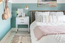 a boho teen bedroom with color block walls, a wooden bed with neutral bedding, a printed rug, an artwork is cool