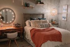 a boho teen bedroom with grey walls, a bed with a reclaimed headboard, a vanity as a makeup table, a bright rug and potted plants