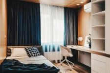 a bold minimalist teen room with a wooden ceiling with lights, navy curtains, a storage unit with a built-in desk, a comfy bed and blue bedding