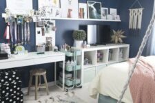 a lovely teen room with navy walls, a turquoise bed, neutral and pastel bedding, a white desk or makeup vanity, a storage unit and a ledge gallery wlal