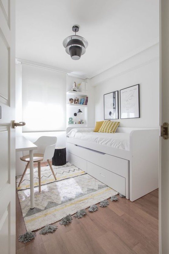 A neutral Scandinavian bedroom with a bed with storage, a desk and a chair, built in shelves and a printed rug