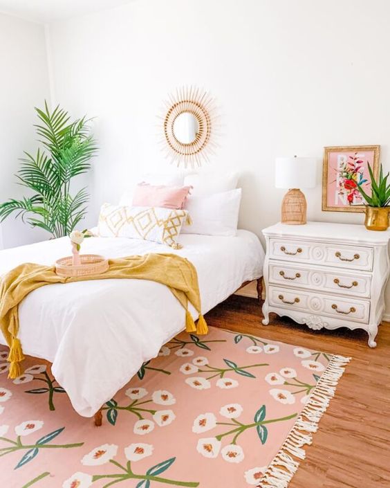 a tropical teen bedroom with a bed with neutral bedding, a pink printed rug, a white inlay dresser, potted plants