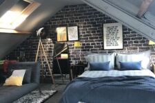 an attic teen bedroom with a brick accent wall, a bed with blue bedding, a grey sofa, a printed rug and some posters