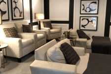 a comfortable and stylish home theater with black walls and a ceiling, neutral seating furniture, dark brown textiles and floor lamps