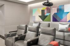 a modern home theater in greys, with grey seating furniture, colorful geometric artwork and built-in lights is a cool space