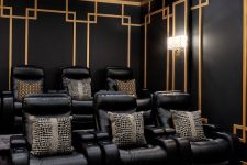 a pretty art deco inspired home theater with black and gold walls, black leather chairs and printed pillows is a stylish and chic space