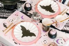 a black, blush and white Halloween tablescape with bat prints all over is a cool idea for a kids’ party