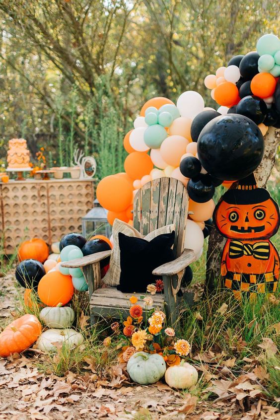 A colorful vintage inspired Halloween space with pastel and bright balloons, a bold cat prop and some blooms and pumpkins