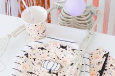 a funny kids’ place setting with printed cups, plates and napkins, neutral pumpkins and a small skeleton