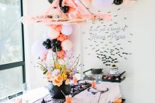 a gorgeous kids’ party space with black witches’ hats, balloons, bold blooms in the cauldron and printed plates