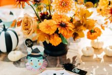 a gorgeous vintage Halloween party tablescape for kids, with bright blooms, fun printed plates and white and striped pumpkins