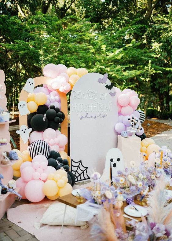 a jaw-dropping pastel kids' party space with lots of balloons, ghosts and some pastel blooms and candles is amazing