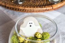 a last-minute Halloween terrarium with pebbles, moss, pinecones, a rock with a ghost is a simple and lovely idea for a kids’ party