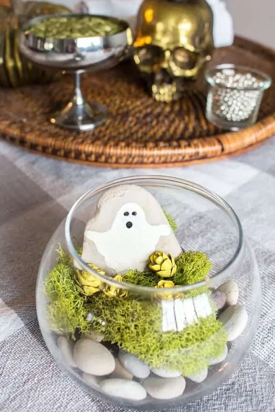 A last minute Halloween terrarium with pebbles, moss, pinecones, a rock with a ghost is a simple and lovely idea for a kids' party